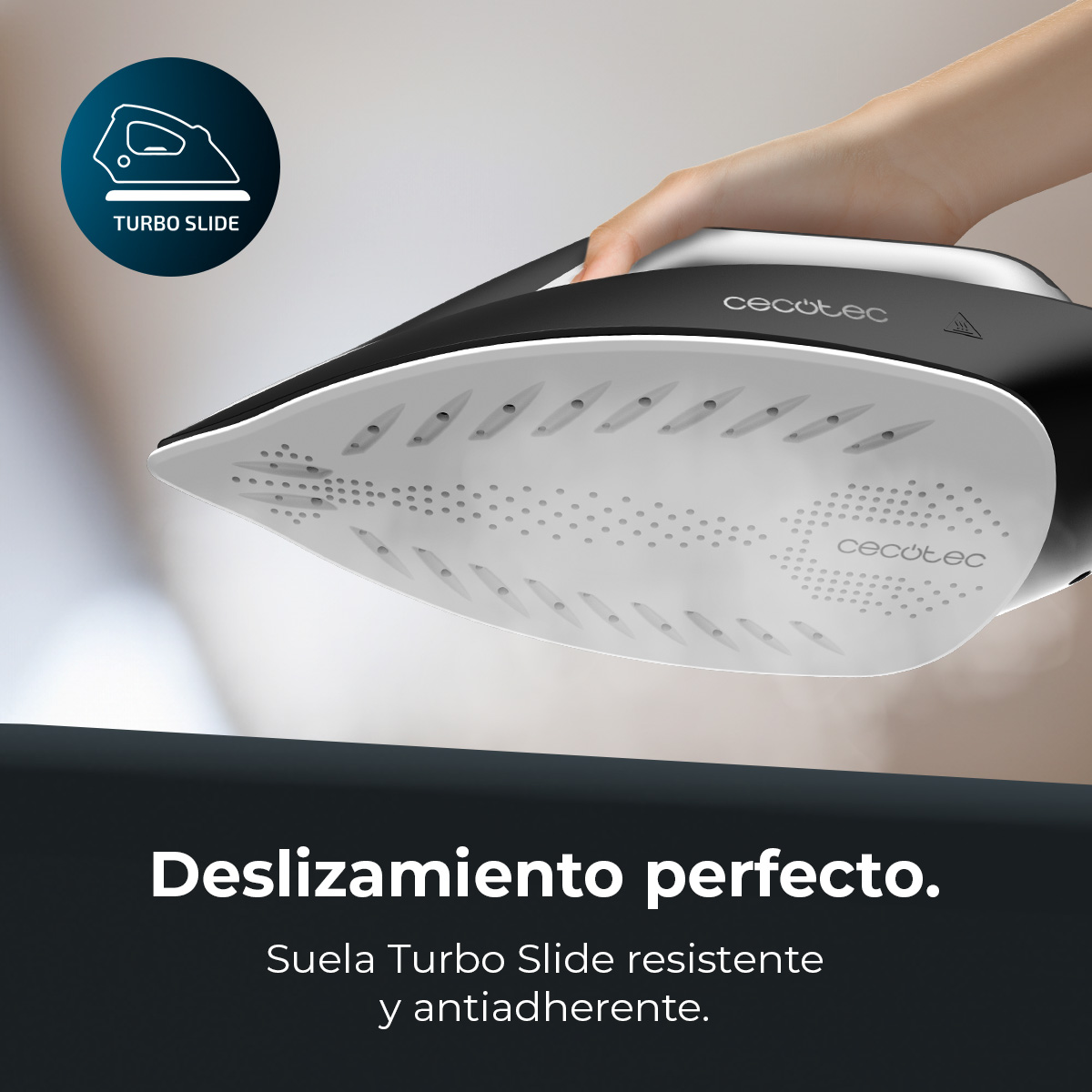 Una plancha en blanco y negro es sostenida por una mano. La suela, Turbo Slide, tiene agujeros. La marca, Cecotec, es visible.