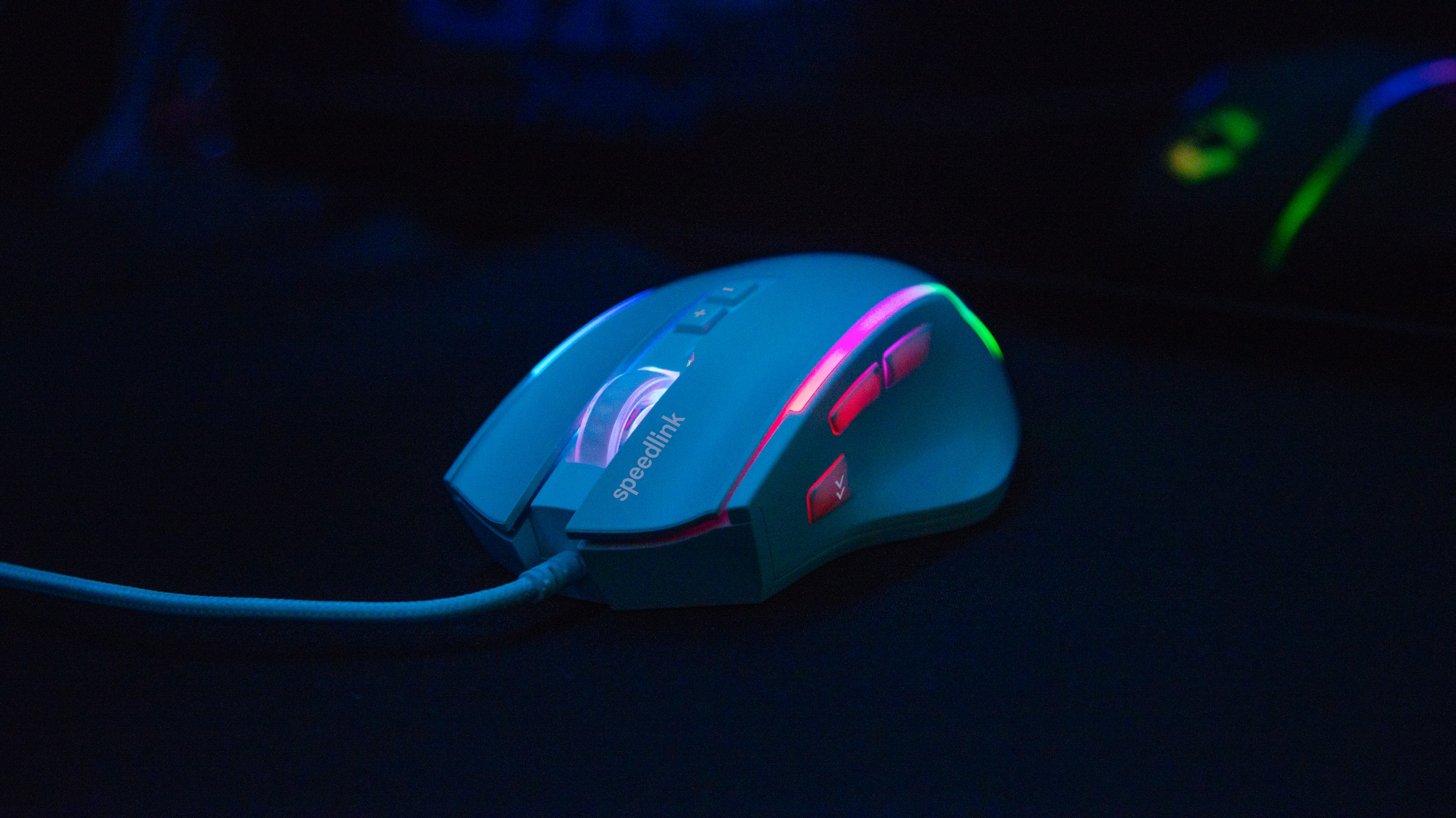 Eine Gaming-Maus mit roten und grünen Lichtern, einem blauen Kabel und dem Speedlink-Logo auf schwarzer Oberfläche.