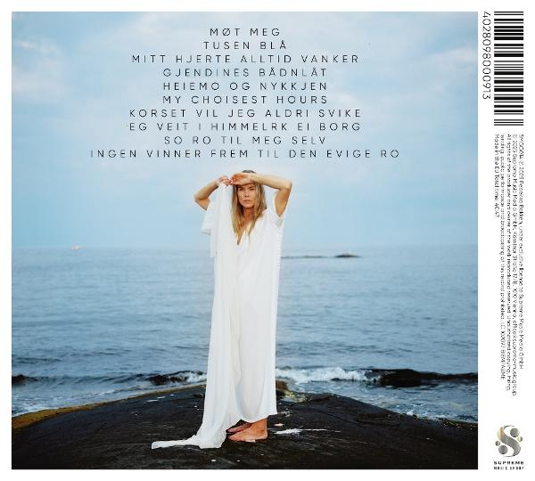 Frau in weißem Kleid steht auf einem Felsen und blickt auf das Meer. Text oben. Barcode rechts.