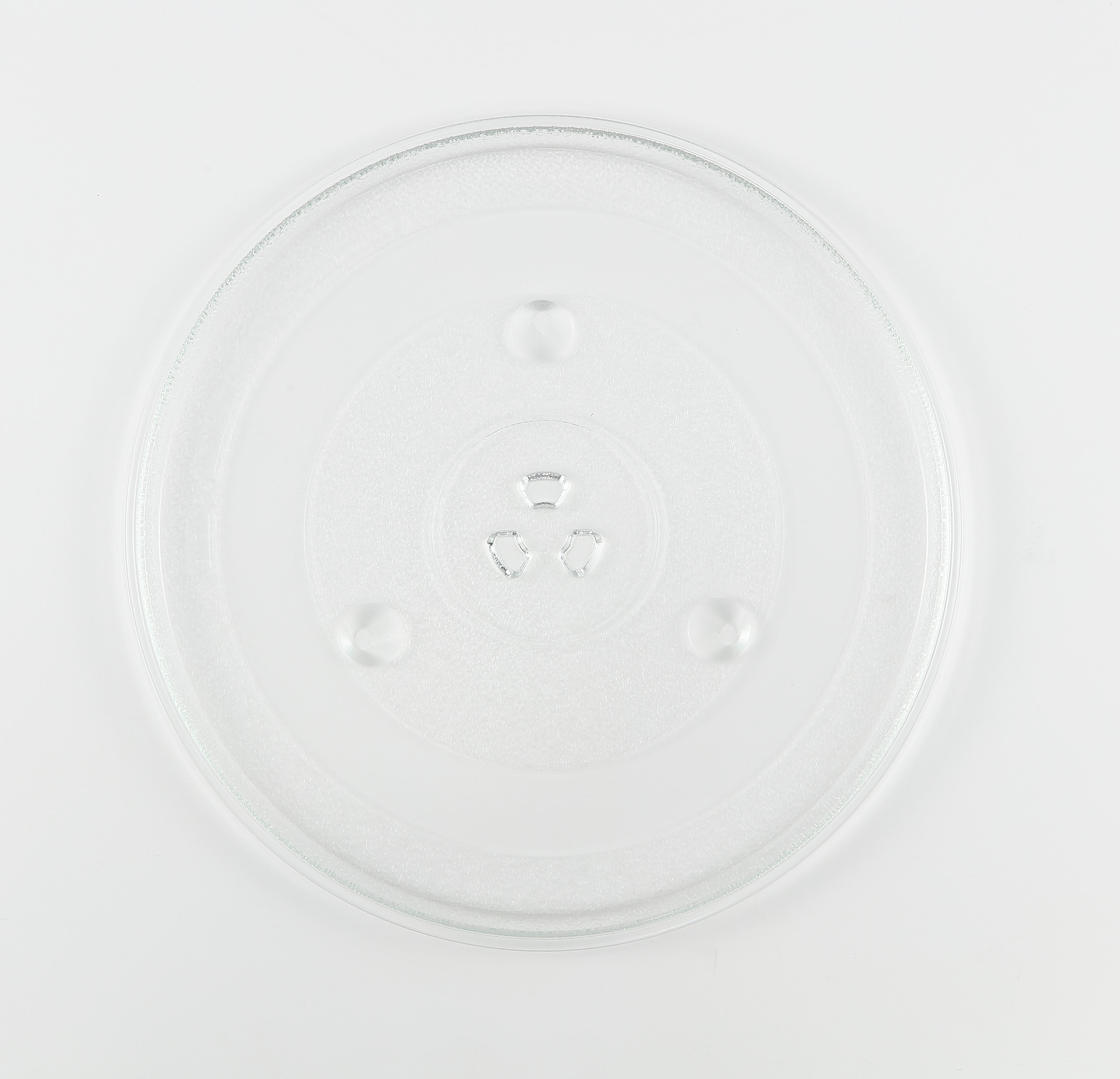 Przezroczysty, okrągły szklany talerz do kuchenki mikrofalowej na białym tle. Ma teksturowaną powierzchnię z trzema małymi wypukłościami i wklęsłościami.