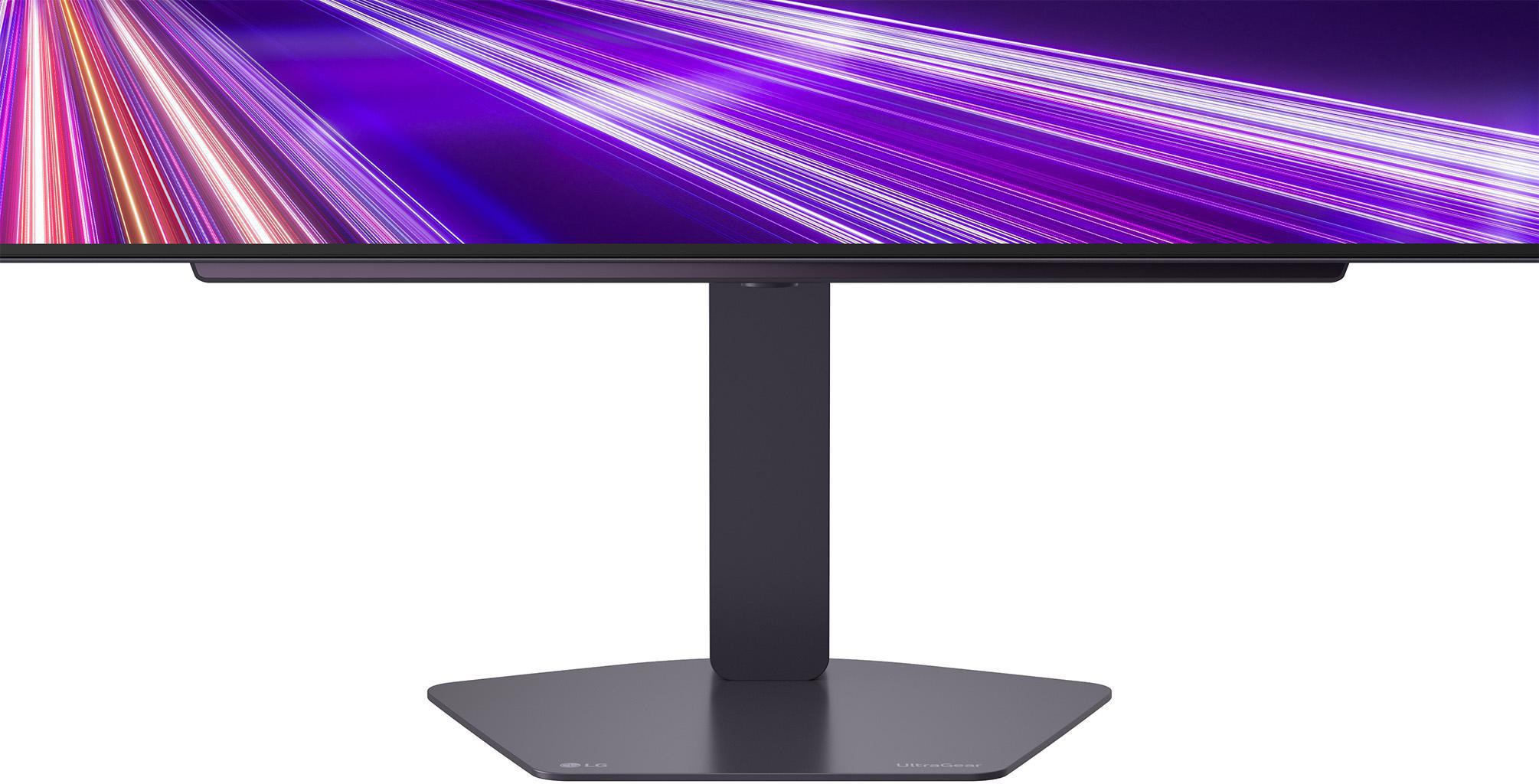 Monitor mit lila und weißen Lichtspuren auf dem Bildschirm, montiert auf einem dunklen Ständer mit sechseckiger Basis.