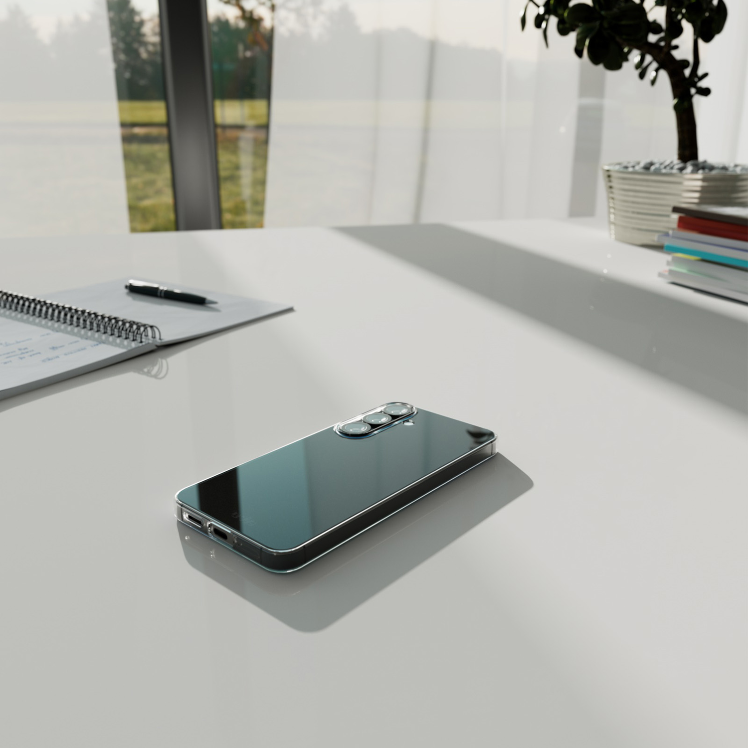Een smartphone ligt op een witte tafel met een pen en notitieboek, een kleine plant en een raam op de achtergrond.