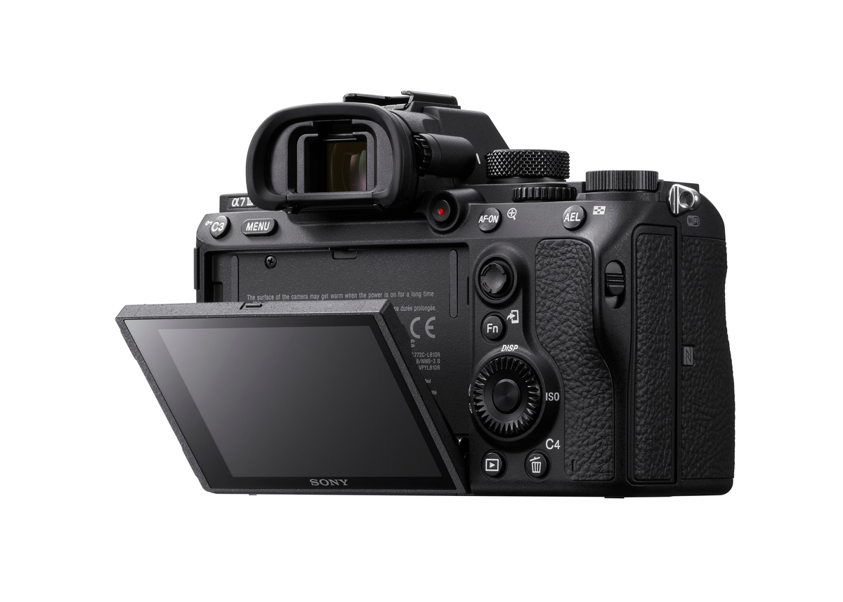 Schwarze Sony Kamera mit geöffnetem Bildschirm. Knöpfe und Räder sind sichtbar. Der Hintergrund ist weiß.