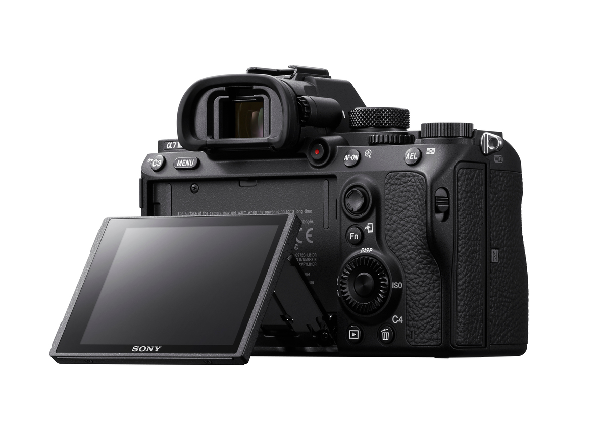 Eine schwarze Sony-Kamera mit offenem Bildschirm wird angezeigt. Knöpfe und Räder sind sichtbar. Der Hintergrund ist weiß.