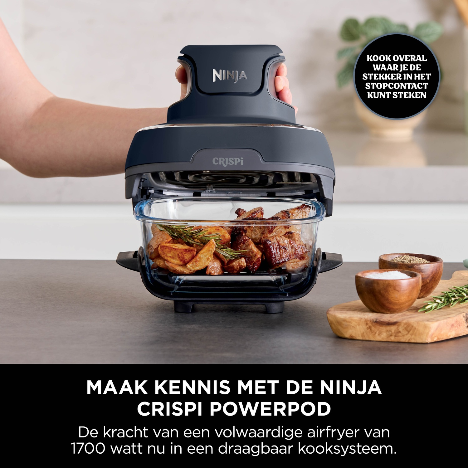 Ninja Crispi Powerpod air fryer with food inside, held by a hand. Spices on wooden board.