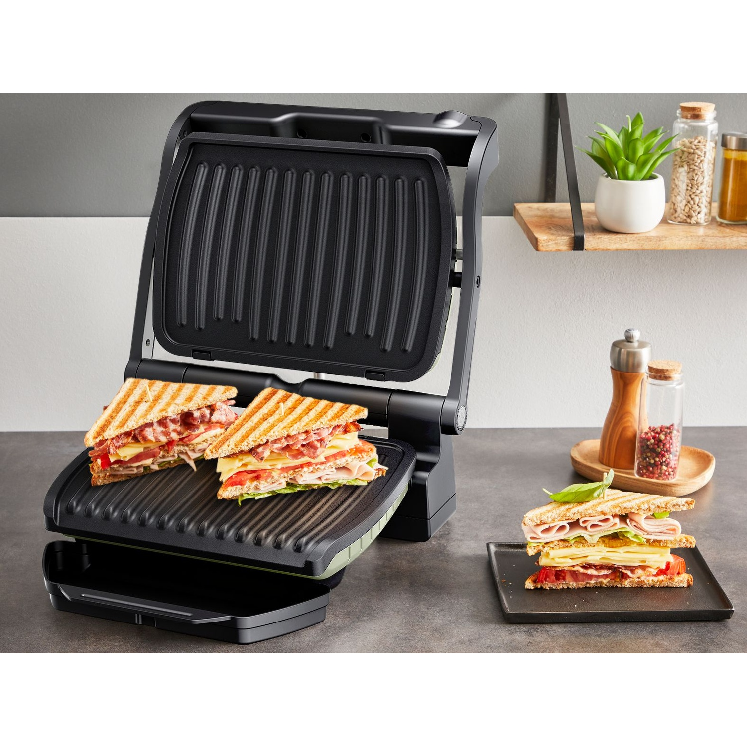Gril ouvert avec deux sandwichs et un sandwich préparé dans une assiette. Ingrédients : fromage, jambon et tomates.