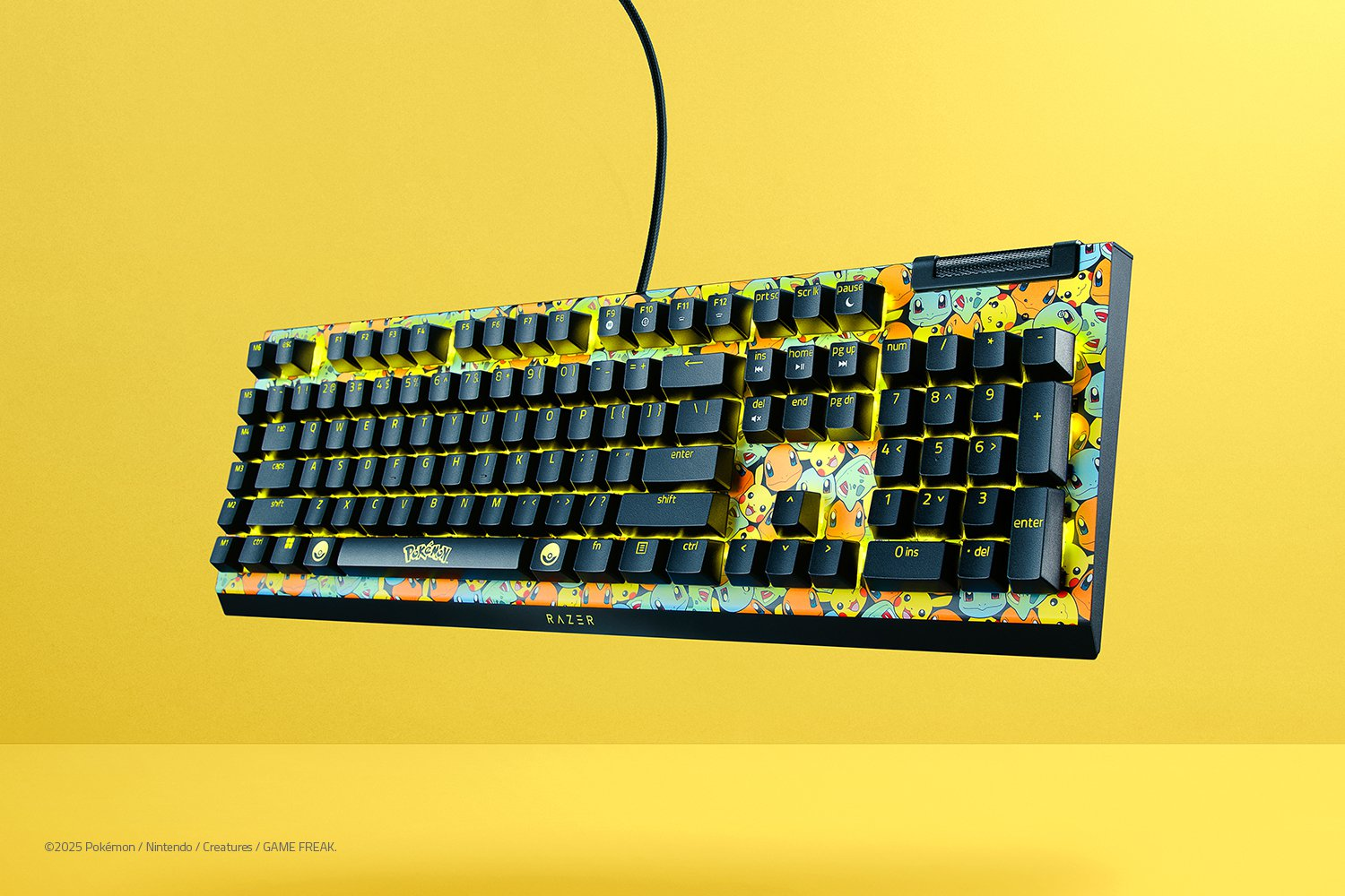 Un teclado colorido con temática de Pokémon sobre un fondo amarillo. El teclado tiene teclas negras y un patrón de Pokémon.