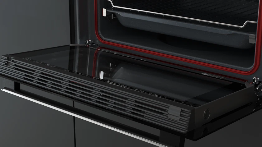 Horno abierto con puerta de cristal negro, junta roja y rejilla metálica interior. El horno está sobre una superficie oscura.
