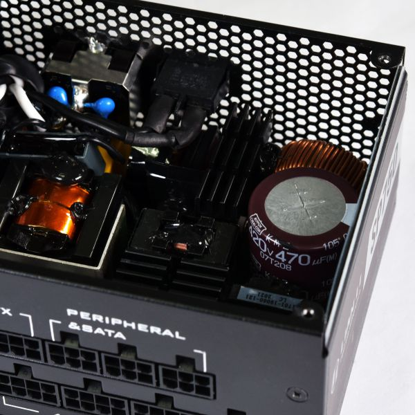 Vista interna di un alimentatore per computer. Mostra condensatori, bobine e vari componenti elettronici all'interno di un involucro metallico.