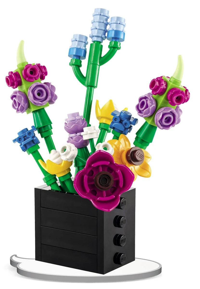 Bukiet LEGO w czarnym wazonie. Kwiaty wykonane są z kolorowych klocków: różowych, fioletowych, żółtych i niebieskich. Zielone łodygi i liście.