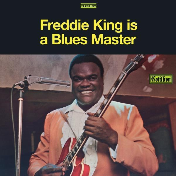 Albumcover von Freddie King mit roter Gitarre. Er lächelt und trägt einen orangenen Anzug. Text: 'Freddie King is a Blues Master'.