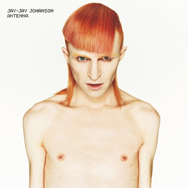 Eine Person mit orangefarbenem Haar und heller Haut, starrt. Das Haar ist mit einem Seitenscheitel und langen Strähnen versehen. Weißer Hintergrund.