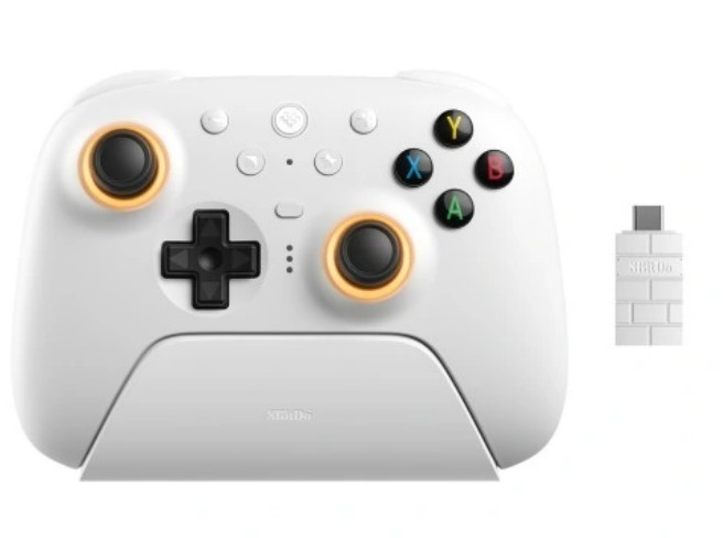 Biały kontroler do gier z pomarańczowymi akcentami i małym białym adapterem. Przyciski: Y, X, A, B. Czarny joystick i D-pad.