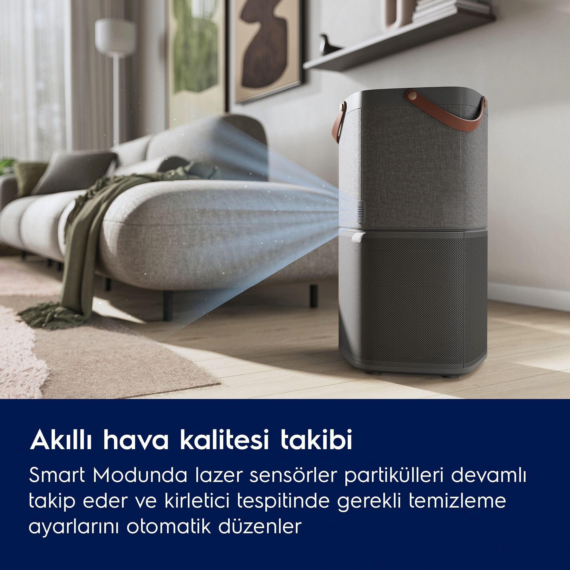Bir hava temizleyici oturma odasında. Bir tutamağı var ve gri renkte. Arka planda bir kanepe ve halı var.