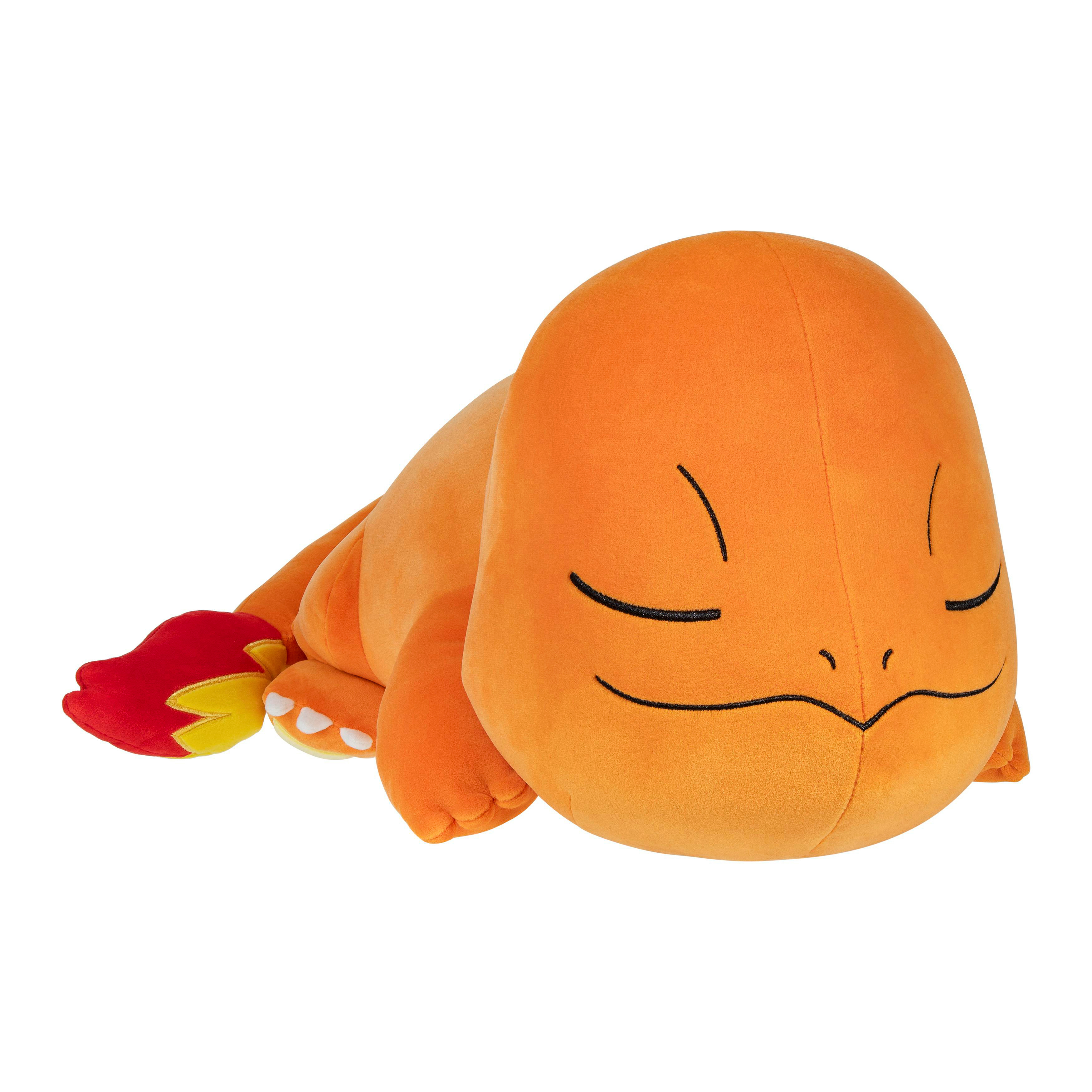 Ein orangefarbenes Charmander-Plüschtier liegt auf der Seite, die Augen geschlossen, mit einem roten und gelben Flammenschwanz.