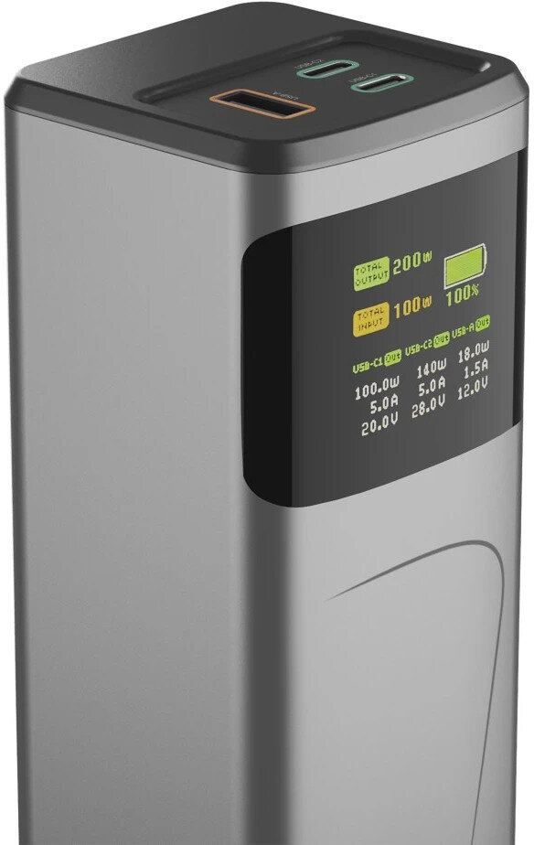 Srebrny power bank z czarną górą i ekranem wyświetlającym informacje o wyjściu i wejściu, a także portami ładowania.