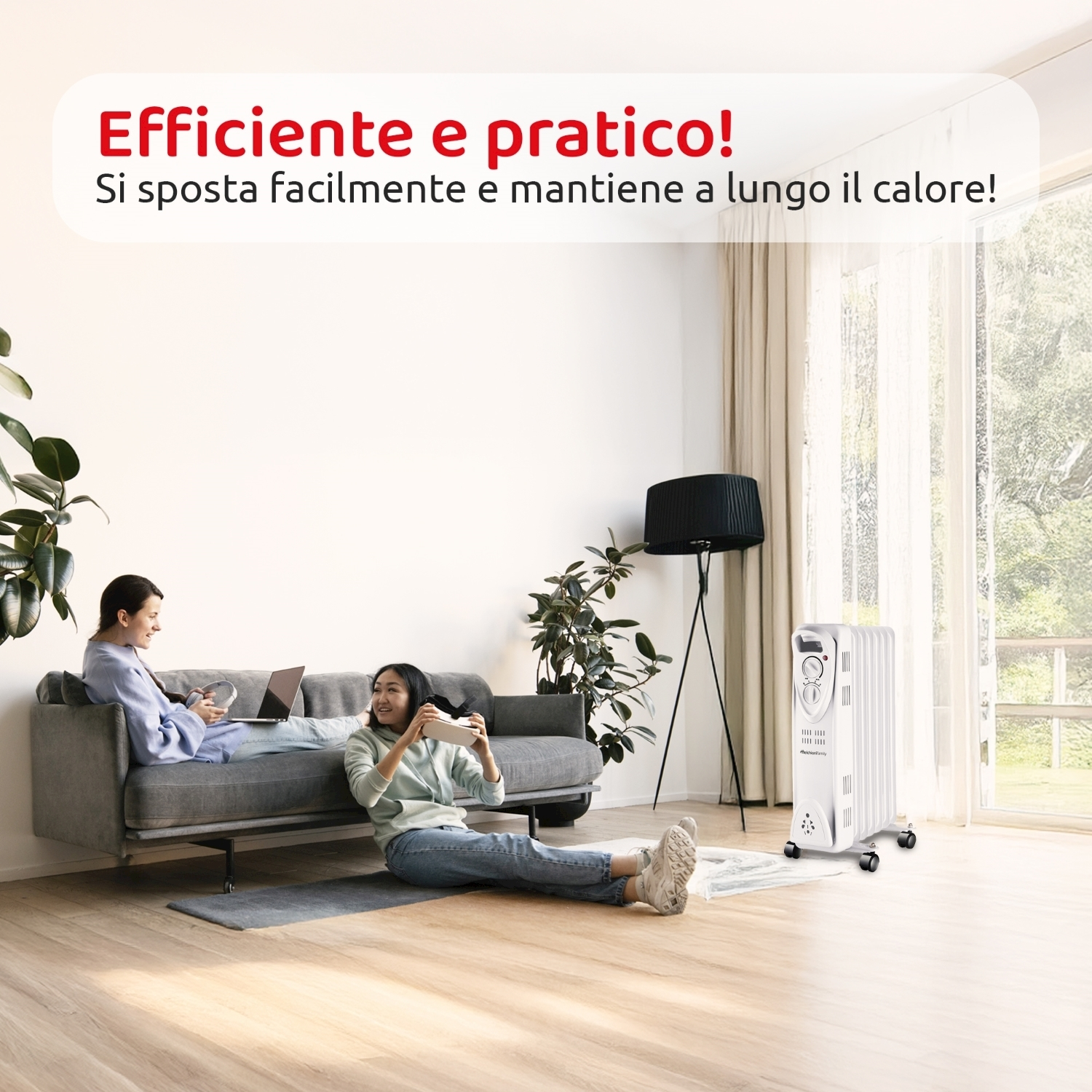 Due donne si rilassano. Una su un divano con un laptop, l'altra sul pavimento con un dispositivo. Un termosifone bianco a destra.
