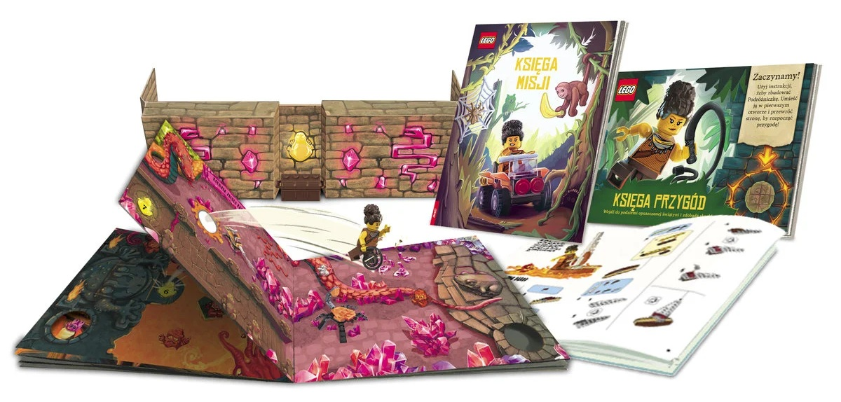 Obraz przedstawia otwarte książki i dioramę. Książki mają markę LEGO i ilustracje. Diorama przedstawia ceglany mur i postać na wózku inwalidzkim.