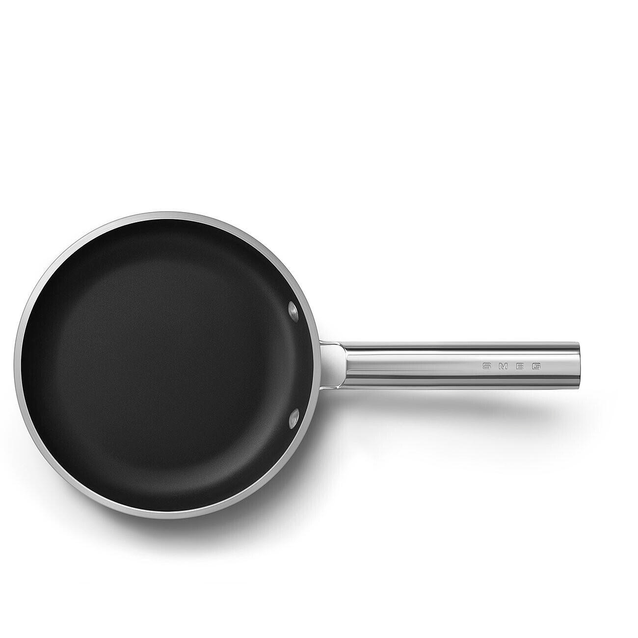 Eine schwarze Bratpfanne mit silbernem Griff auf weißem Untergrund. Die Pfanne hat einen dunklen Innenraum und einen glänzenden Silberrand.