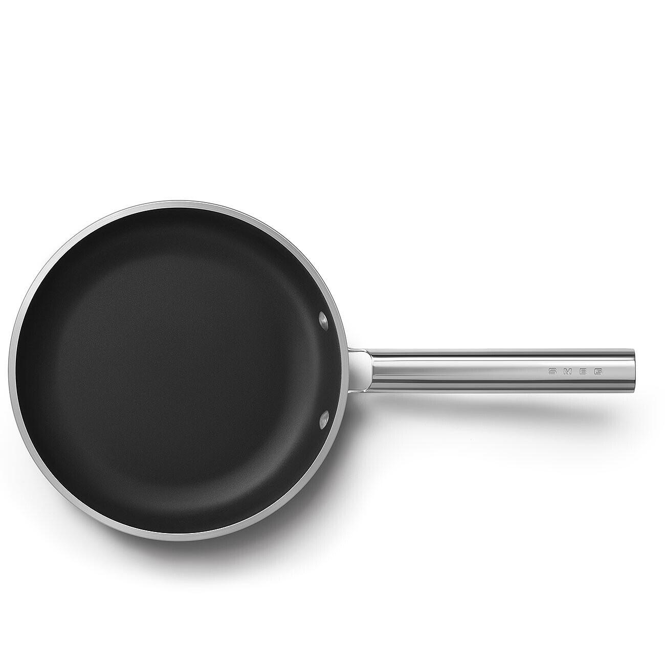 Eine schwarze Bratpfanne mit silbernem Griff. Die Pfanne liegt auf einer weißen Oberfläche. Der Griff hat das Wort SMEG.