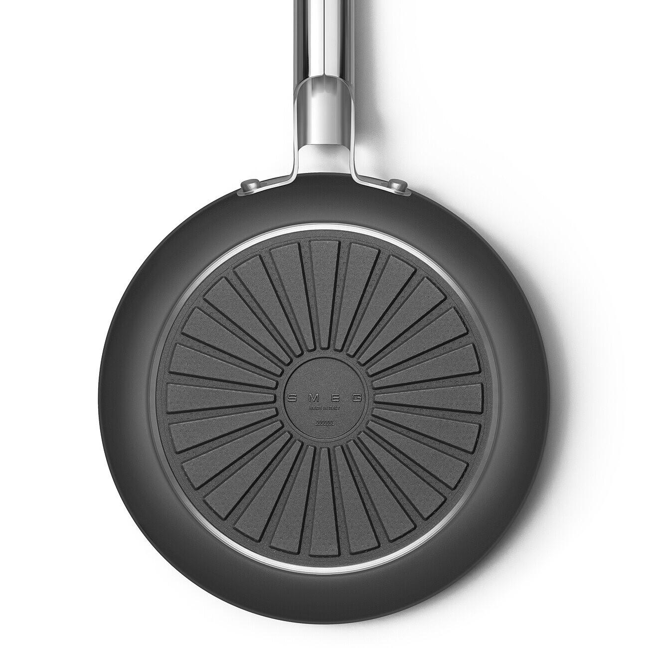 Der Boden einer schwarzen Bratpfanne wird gezeigt. Der Griff ist silberfarben. Die Basis hat ein strukturiertes, kreisförmiges Design mit dem SMEG-Logo.