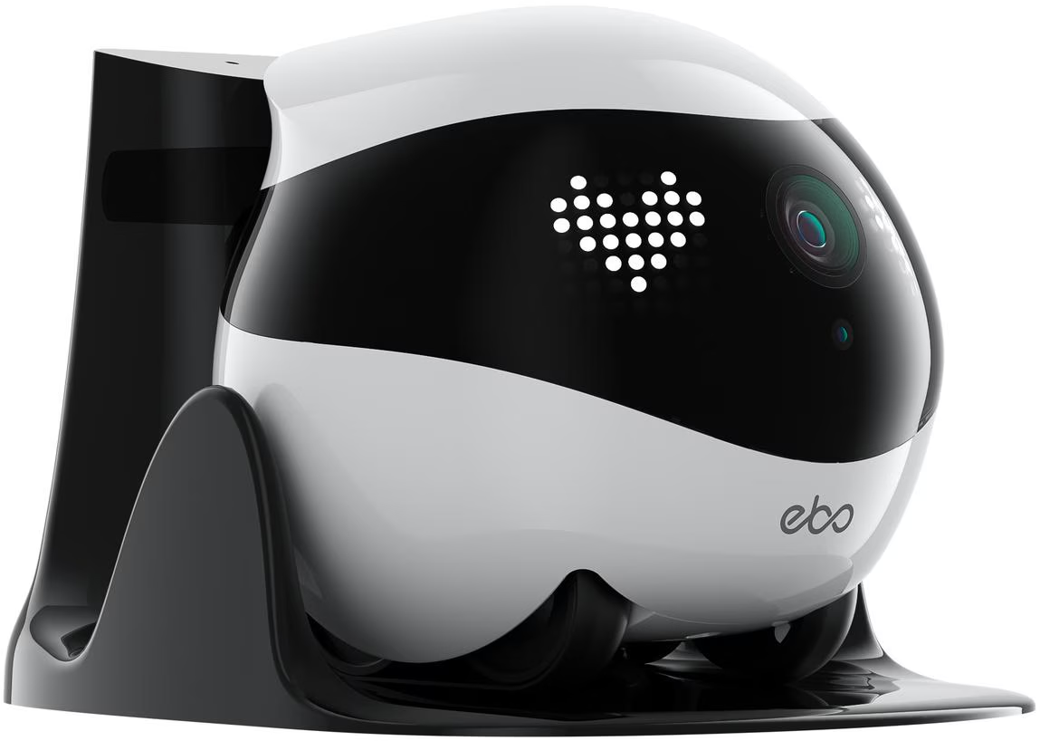 Ein weiß-schwarzer Roboter in einer schwarzen Ladestation. Der Roboter hat ein herzförmiges Display und eine Kamera.