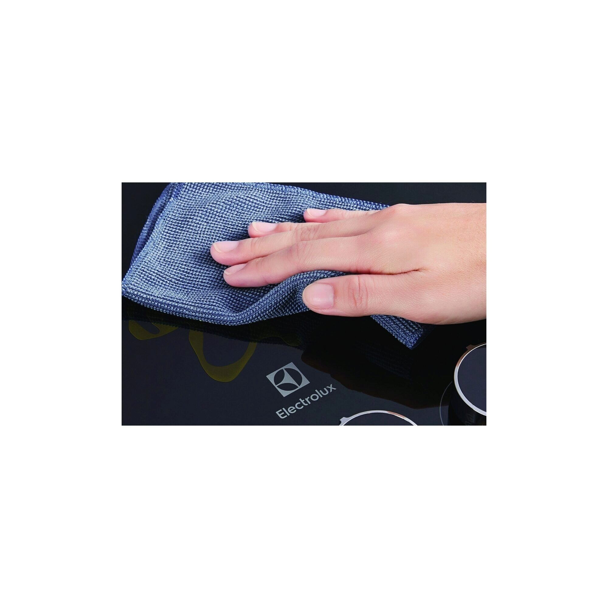 Mavi bir bezle siyah bir ocak üstünü silen bir el. Electrolux logosu görünür.
