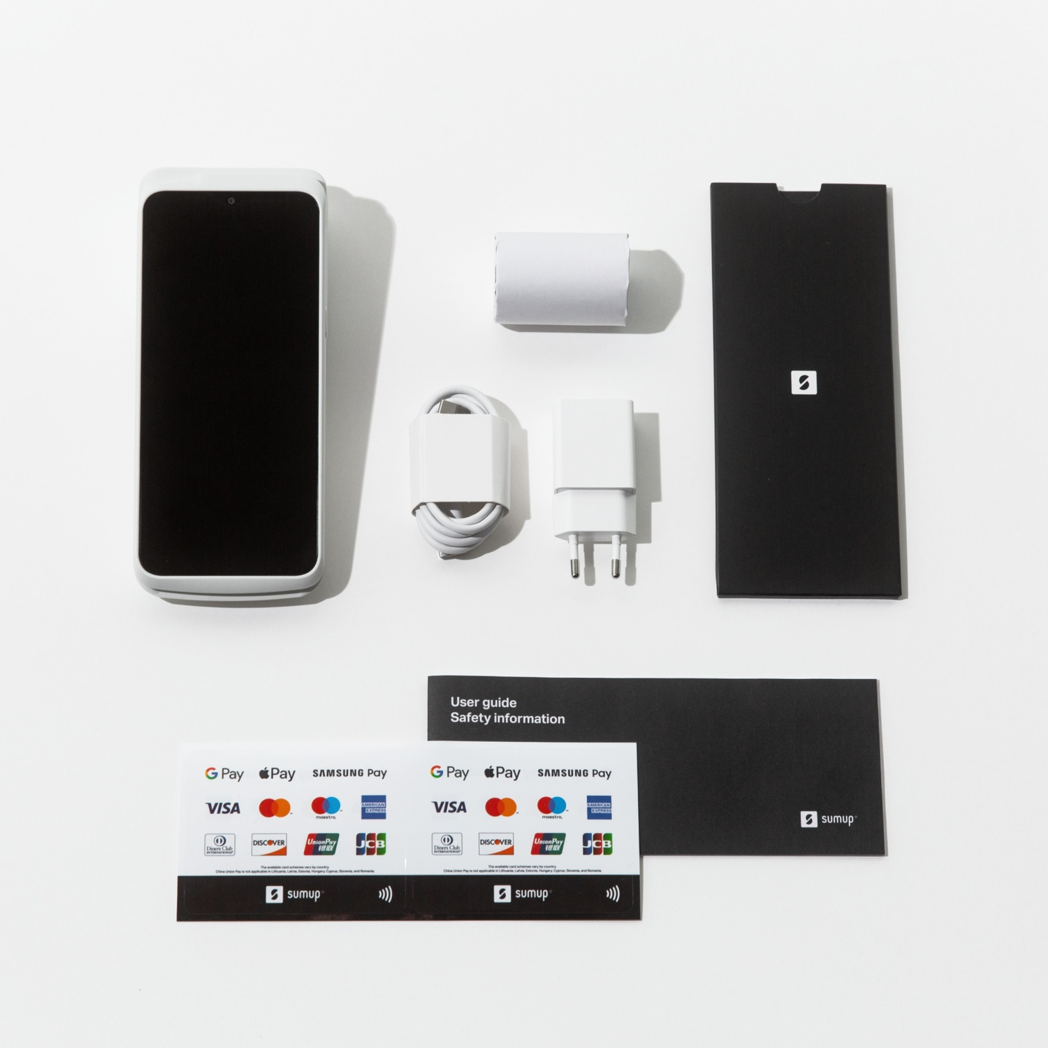 Uno smartphone, caricabatterie, cavo e scatola su una superficie bianca. Due carte con loghi di pagamento e una guida per l'utente.
