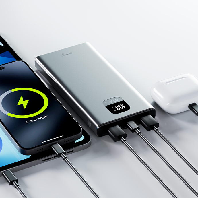 Egy telefon és egy tablet egy power bankról töltődik. A fülhallgató is töltődik. A telefon 67%-os töltöttséget mutat.
