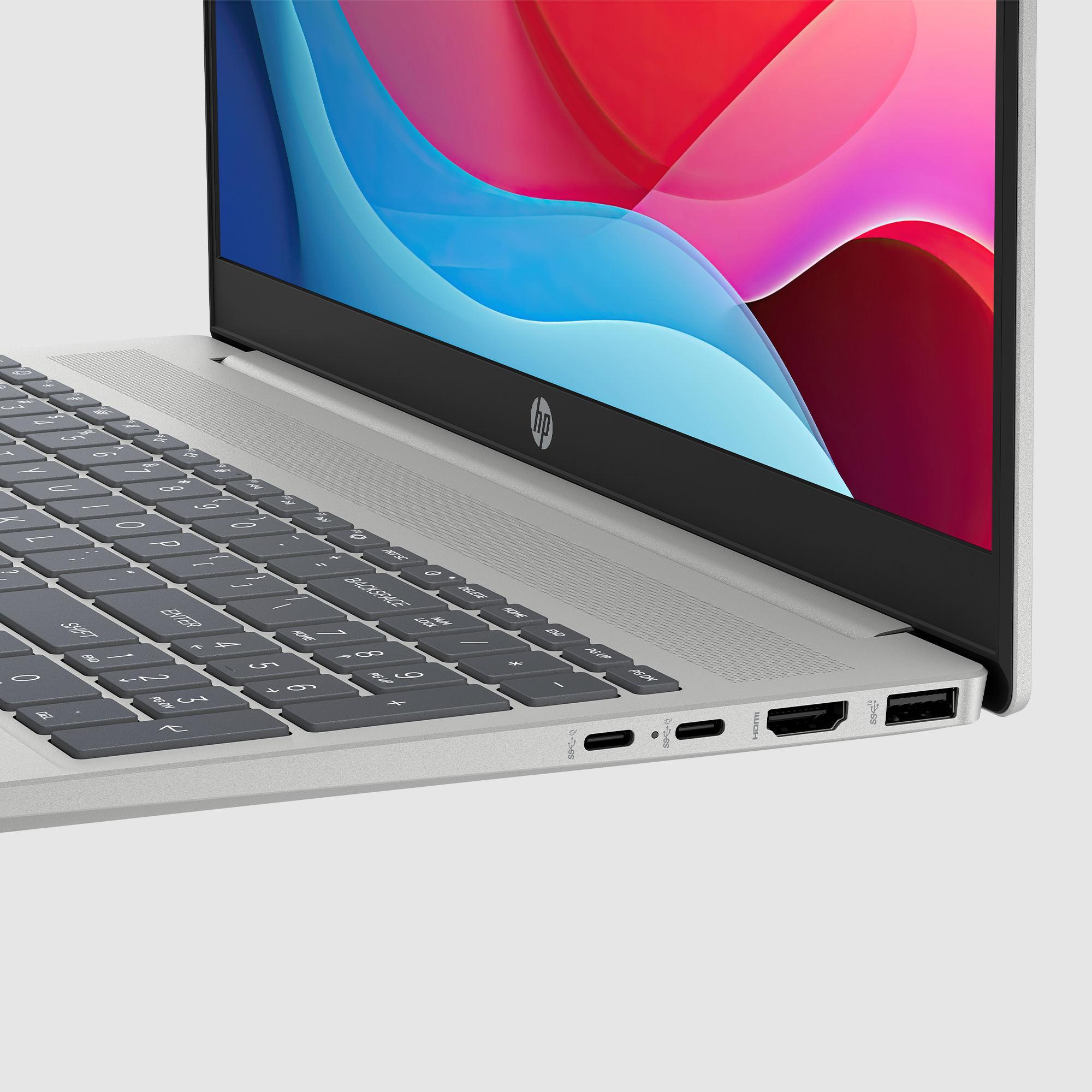 Srebrny laptop, klawiatura w centrum. Wyświetlacz z kolorowymi abstrakcyjnymi kształtami. Logo HP na ramce ekranu.