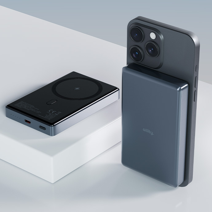Egy fekete power bank és egy sötétszürke telefon, egy power bankkal. Mindkettő fehér felületen van.