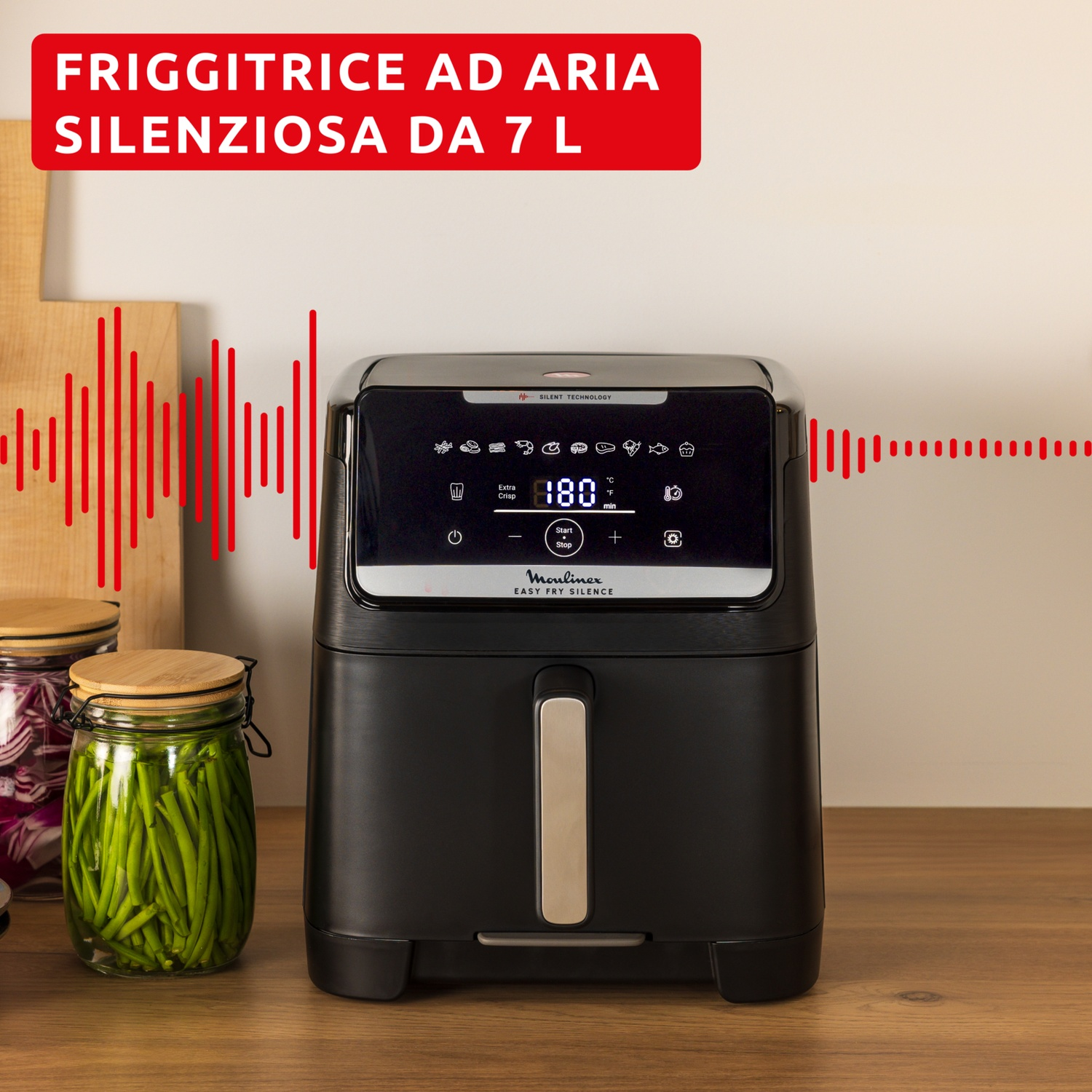 Una friggitrice ad aria nera con display digitale a 180°C. Barattoli di verdure su legno. Testo: 'FRIGGITRICE AD ARIA'.