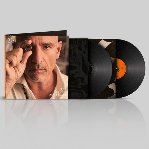 Férfi gyűrűt tart a szeme elé. Album borítója férfivel és szöveggel. Vinil lemezek jobbra.