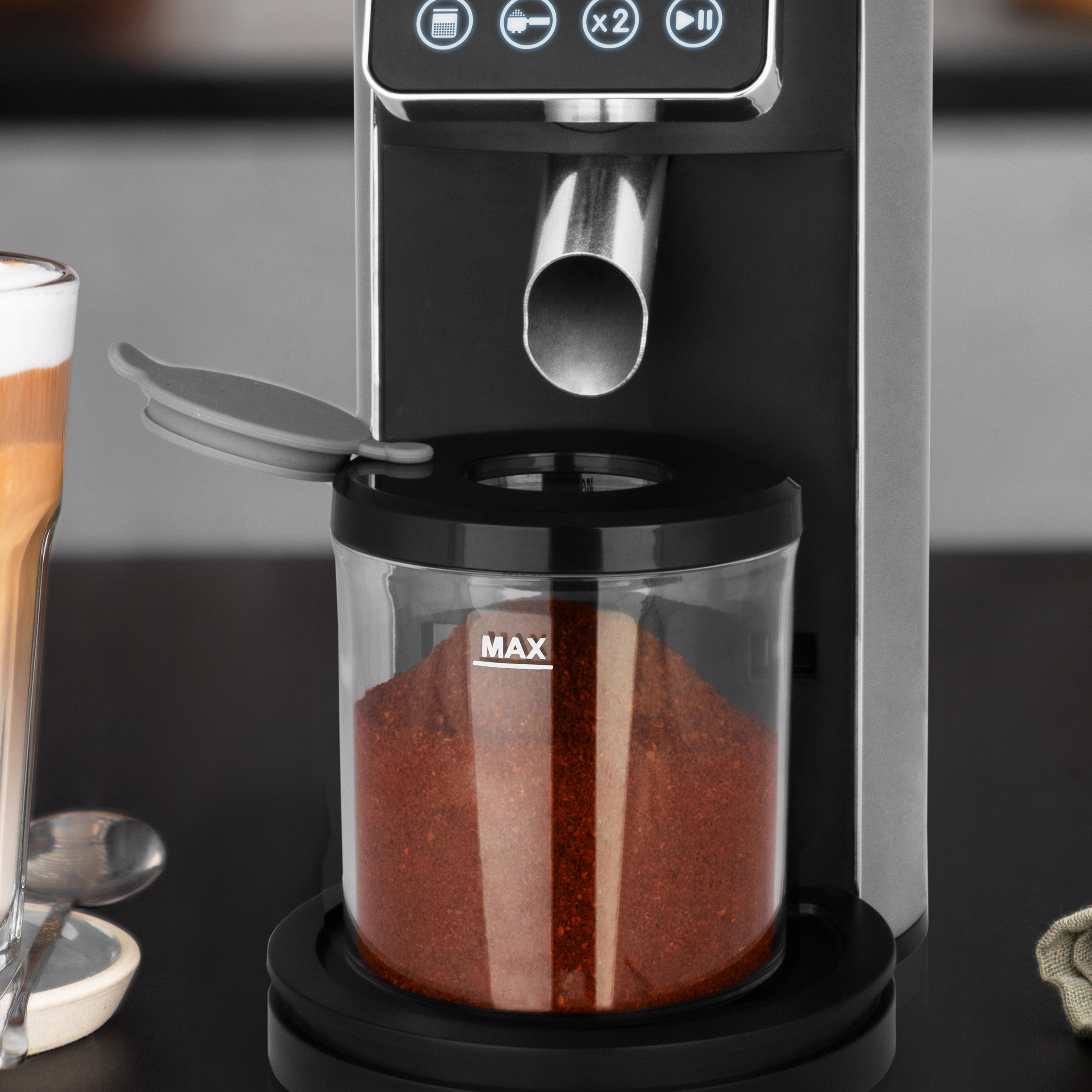 Kaffeemaschine mit Behälter für Kaffeepulver, Latte und Löffel.