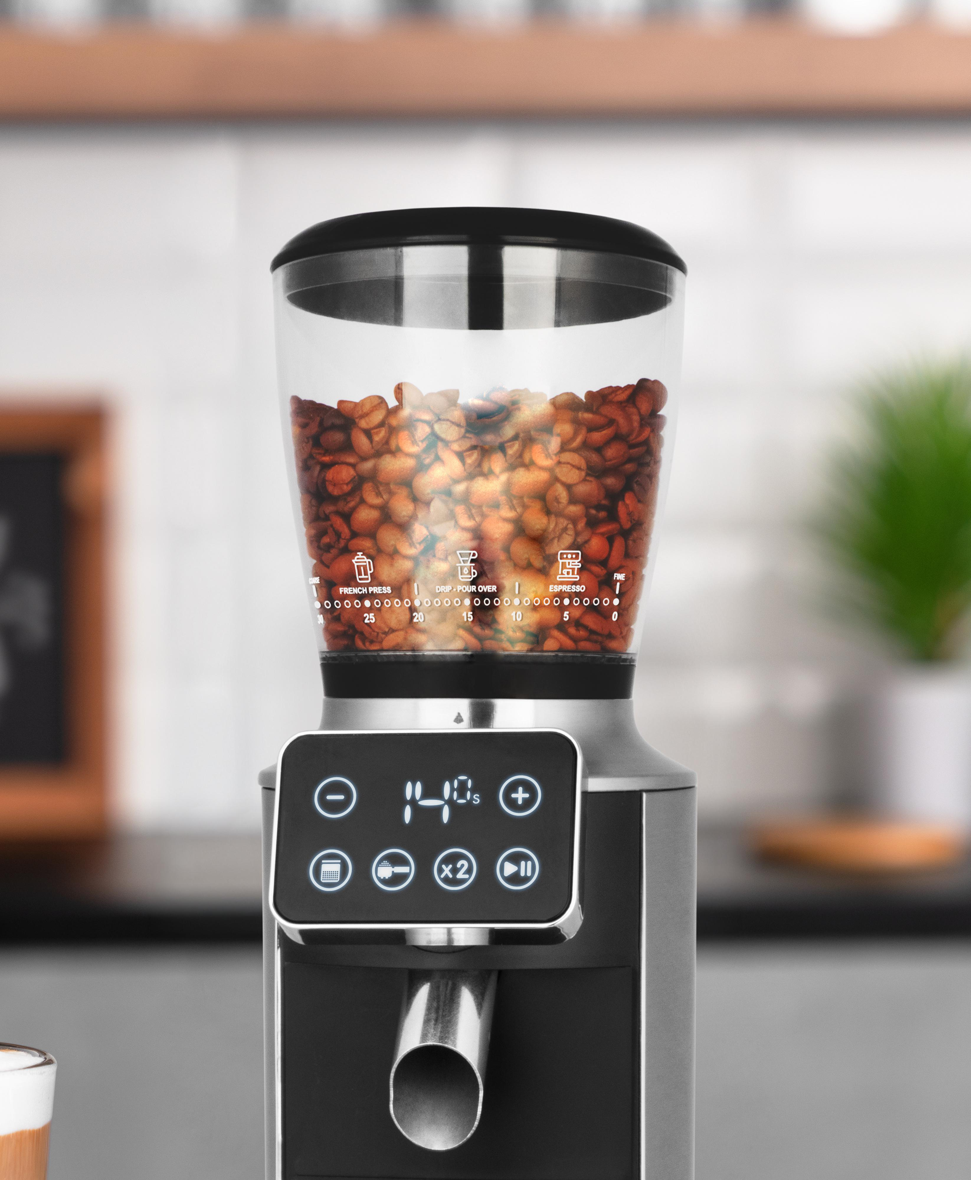 Kaffeemühle mit Bohnen. Digitalanzeige zeigt 140s. Tasten für Einstellungen. Hintergrund verschwommen, weiße Fliese.