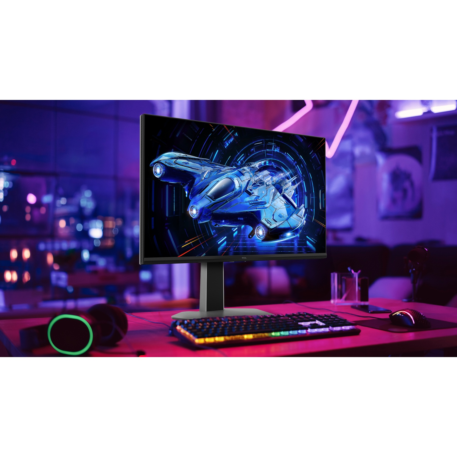 L'écran affiche un vaisseau spatial bleu futuriste. Clavier, souris et casque sont sur un bureau avec des néons.