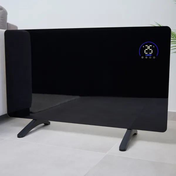 Czarny grzejnik panelowy z cyfrowym wyświetlaczem pokazującym 25 stopni. Stoi na dwóch czarnych nóżkach na podłodze z płytek.