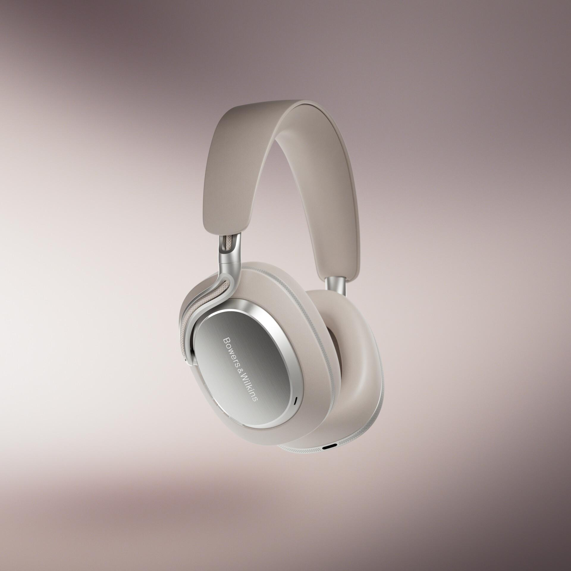 Beige Kopfhörer von Bowers & Wilkins, silberne Akzente, vor einem rosa-farbenen Hintergrund. Markenzeichen auf Ohrmuscheln.