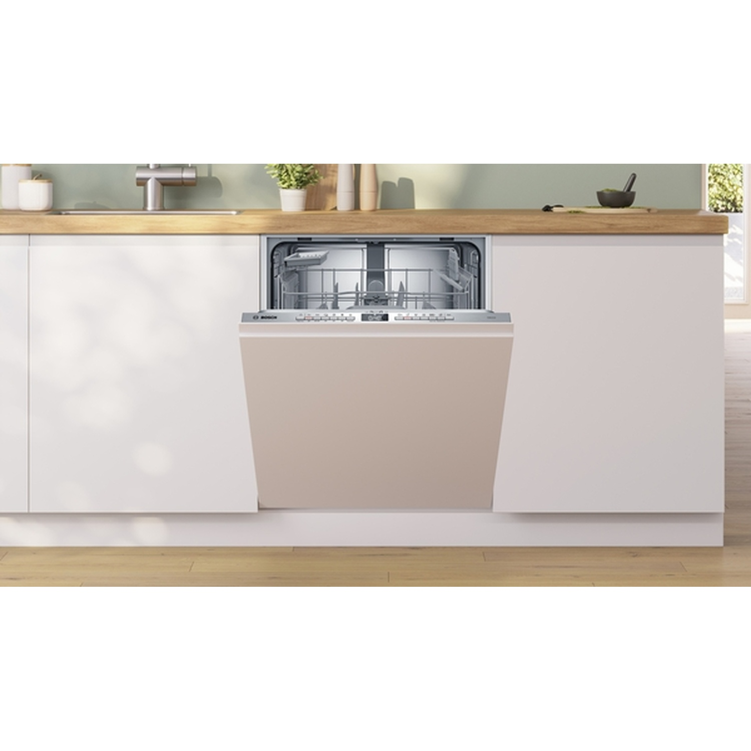 Open vaatwasser in een moderne keuken. Beige deur, roestvrijstalen interieur. Houten aanrecht, witte kasten en een groene muur.