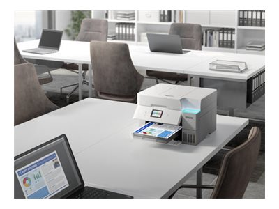 Una scena d'ufficio con una stampante che stampa un documento. Ci sono laptop, sedie e tavoli. Lo sfondo ha delle mensole.