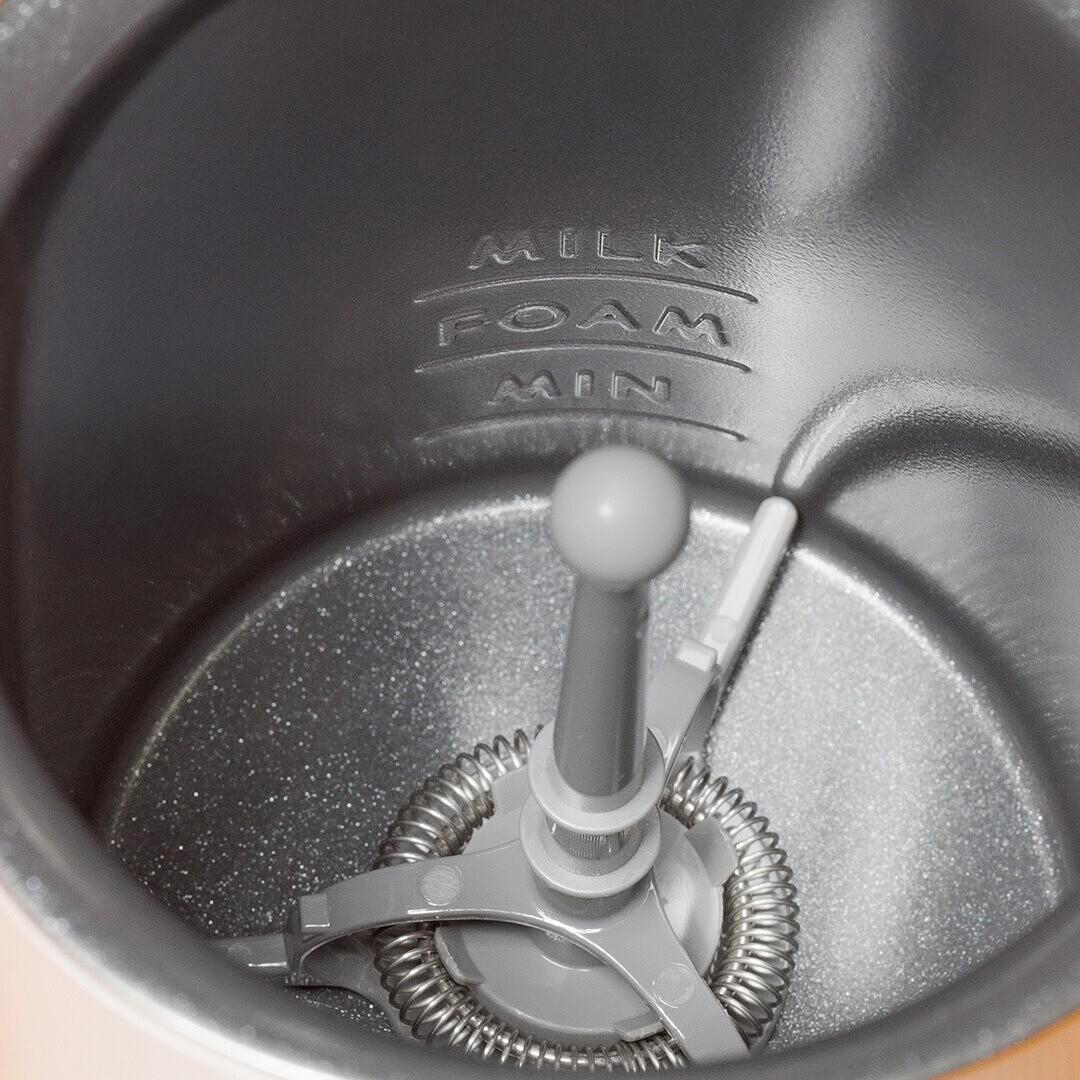 In einem Milchaufschäumer. In der Mitte befindet sich ein grauer Aufschäummechanismus. Im Inneren sind Milchstandmarkierungen.