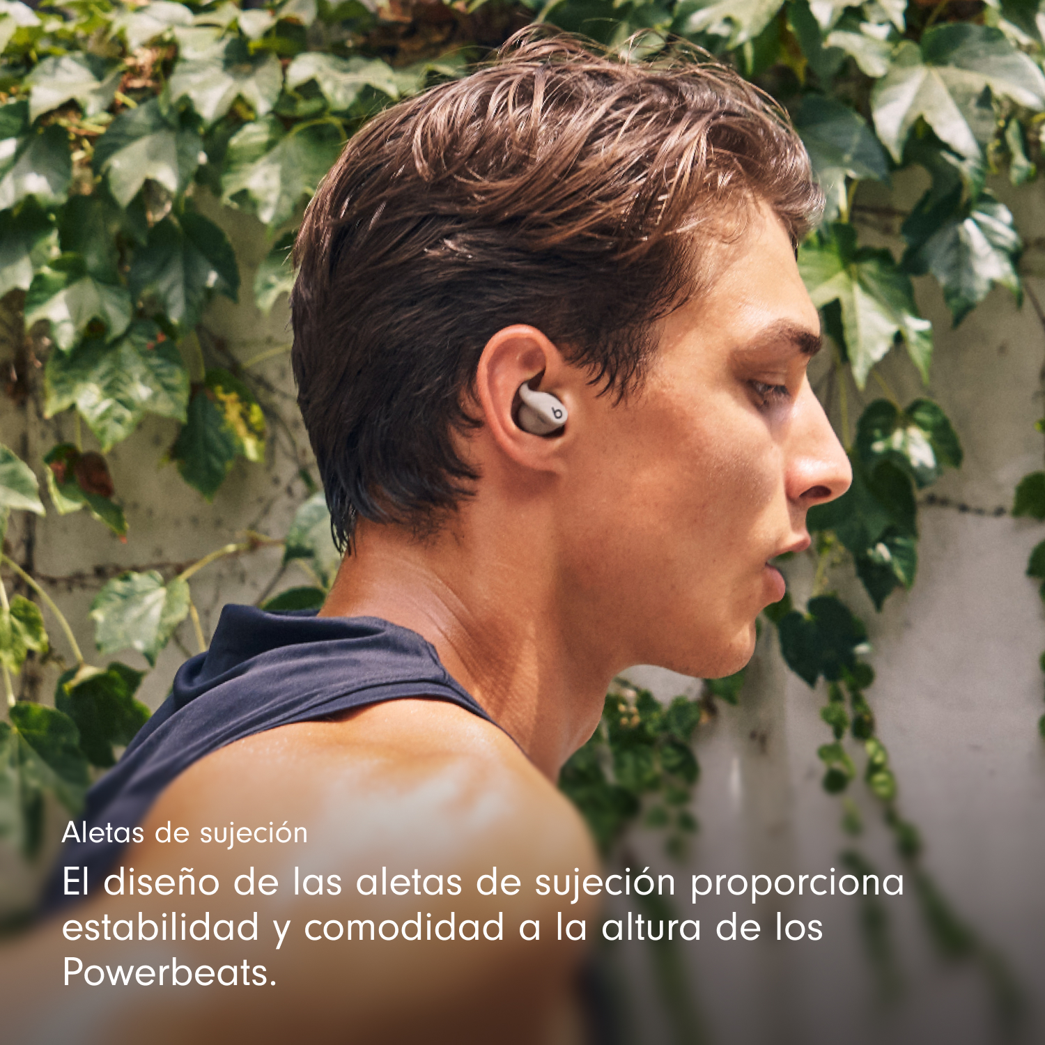 Un hombre con auriculares grises, mirando hacia abajo. Hojas verdes en el fondo. El texto dice 'Aletas de sujeción' y más.