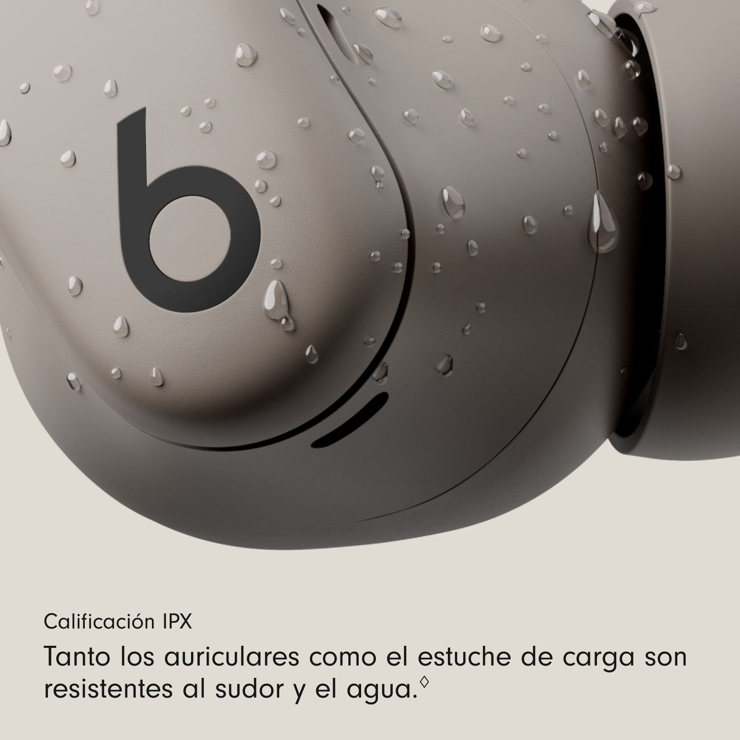 Primer plano de un auricular beige con el logotipo 'b', cubierto de gotas de agua. El texto indica resistencia al sudor y al agua.