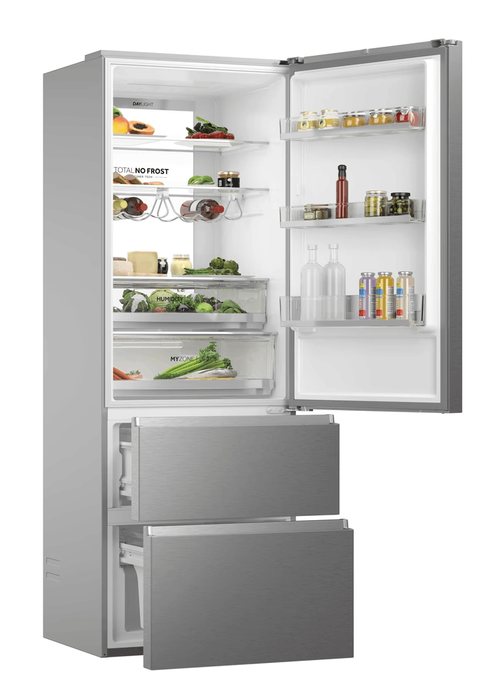 Refrigerador abierto lleno de comida: frutas, verduras, botellas, frascos. Dos cajones están abiertos. Acabado de acero inoxidable.
