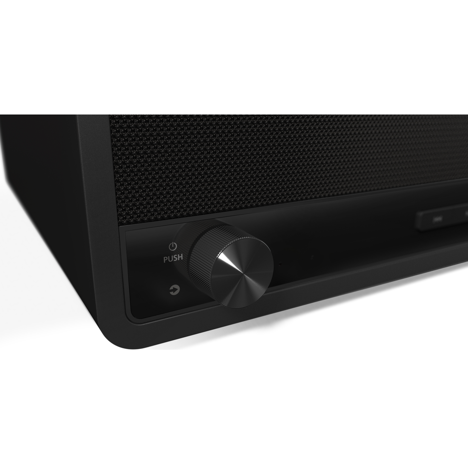 Close-up of a black audio device. A silver knob with a push function is on the front. A speaker grill is to the right.