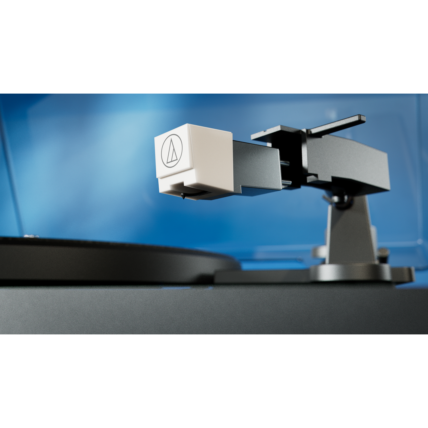 Close-up of a turntable needle. White headshell with logo, black arm, and platter. Blue background.