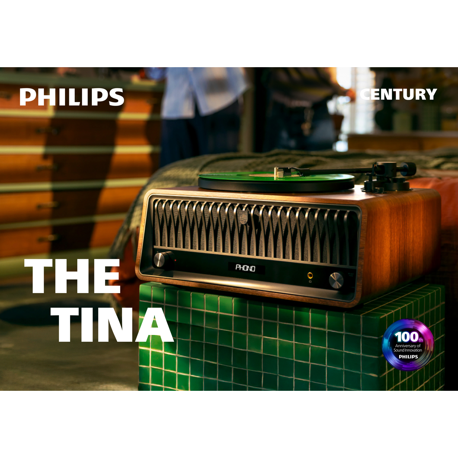 Een vintage platenspeler met een groene plaat staat op een groene tegelstandaard. Het Philips-logo is zichtbaar.