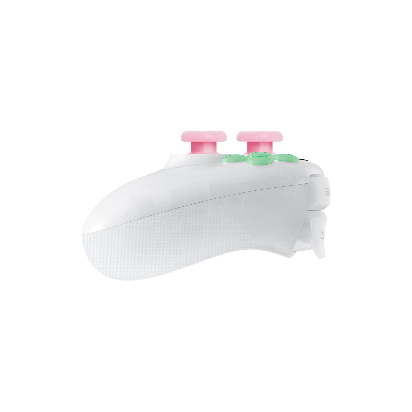 Seitenansicht eines weißen Gamecontrollers mit rosa und grünen Knöpfen, isoliert auf weißem Hintergrund.