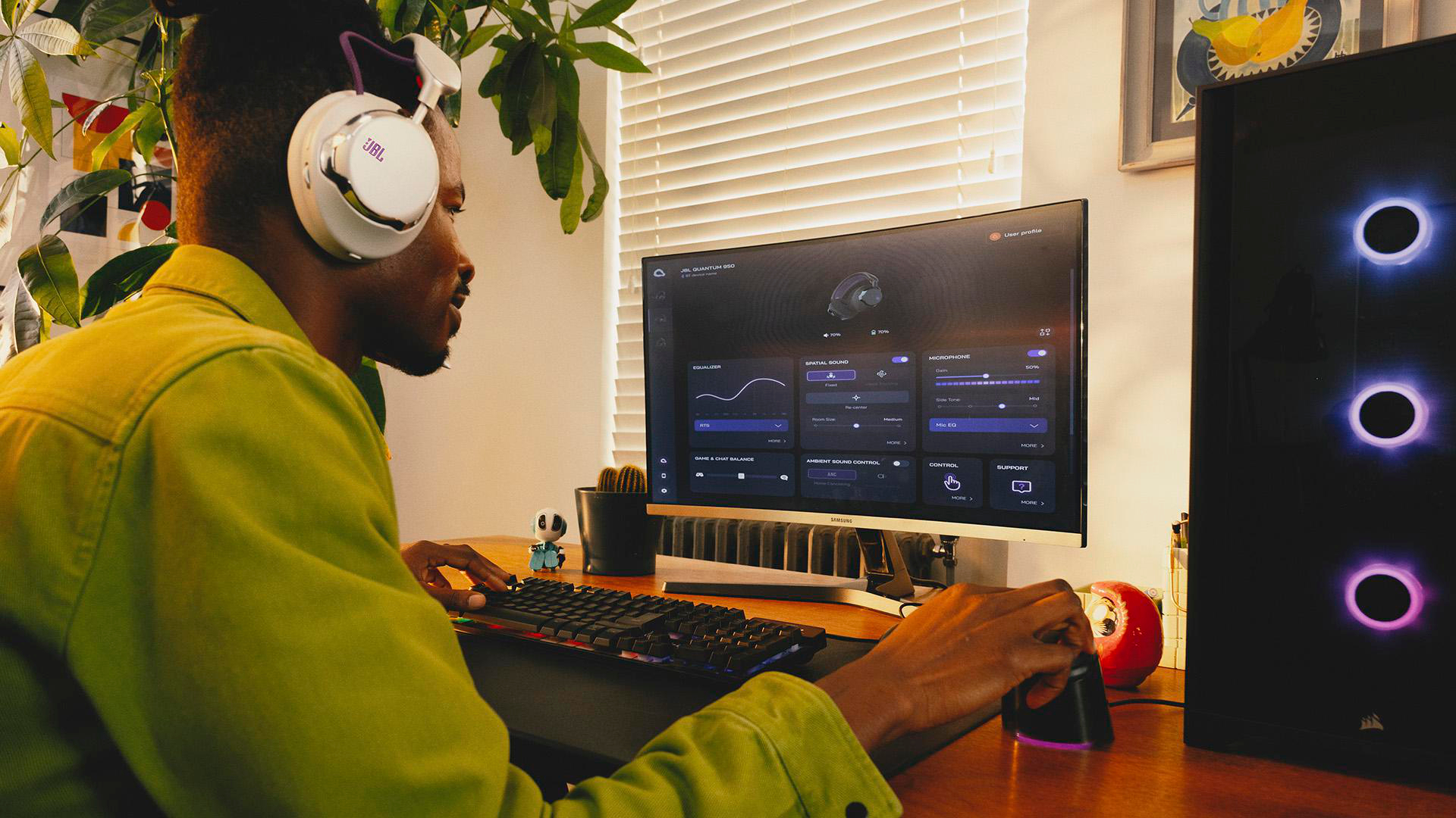 Eine Person mit Kopfhörern benutzt einen Computer. Der Monitor zeigt Softwareeinstellungen an. Rechts ist ein PC-Tower mit leuchtenden Lichtern.