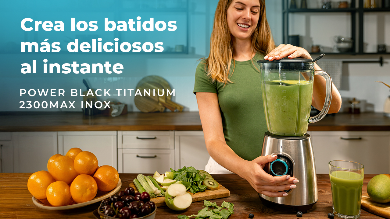 Mujer haciendo un batido con una licuadora. Naranjas, manzanas, kiwi y cerezas en la encimera.